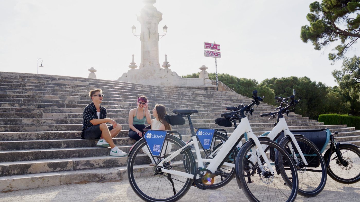 Three people with Clover electric bikes beside the old Turia riverbed in Valencia